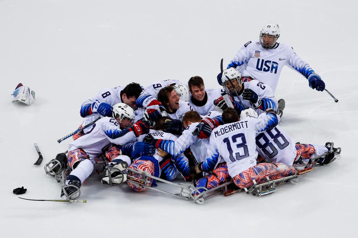 a group of Para ice hockey players celebrate on the ice