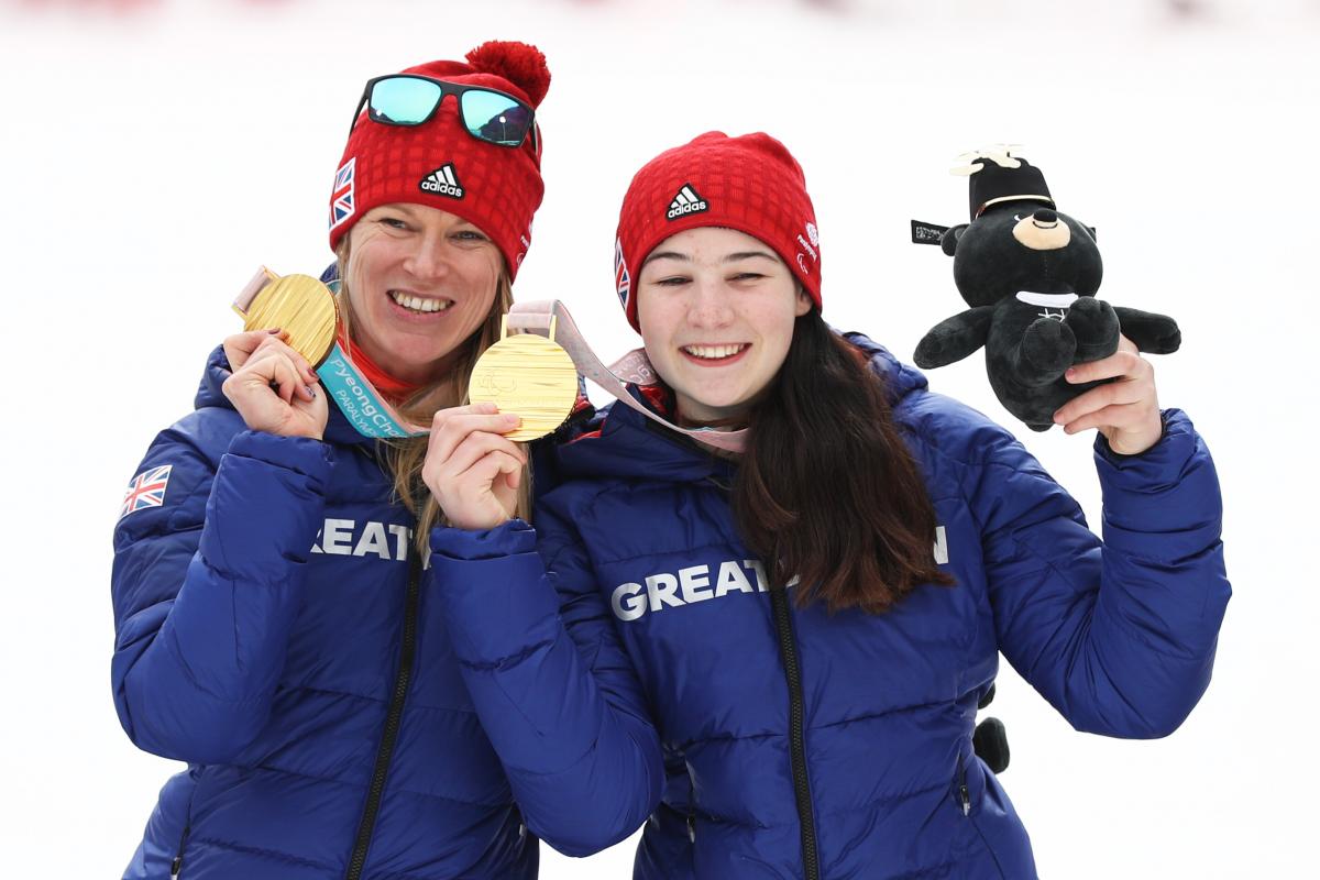 two female alpine skiers with gold medals on the podium