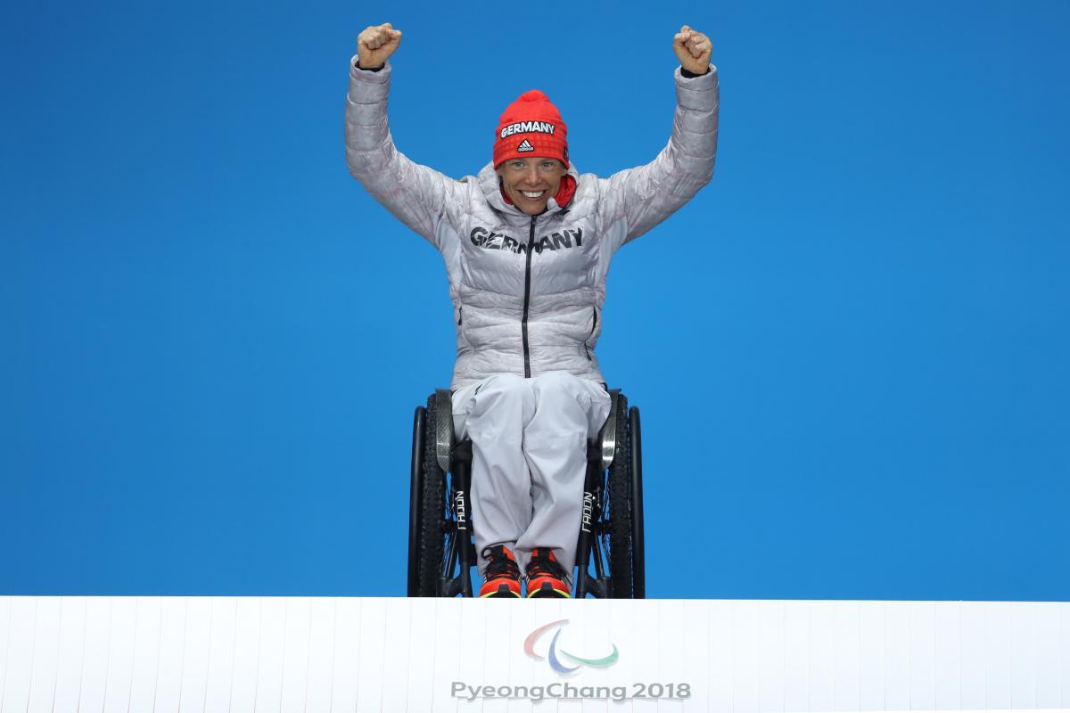 Andrea Eskau - PyeongChang 2018 a wheelchair athlete raises her arms on the podium