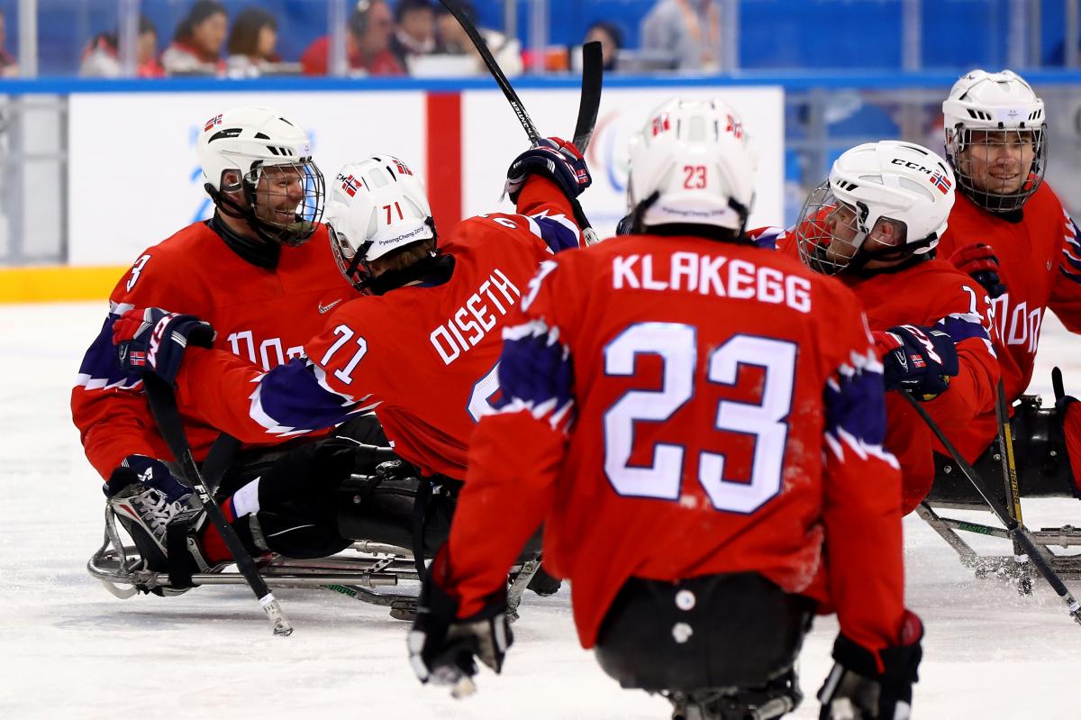 a group of Para ice hockey players celebrate a goal