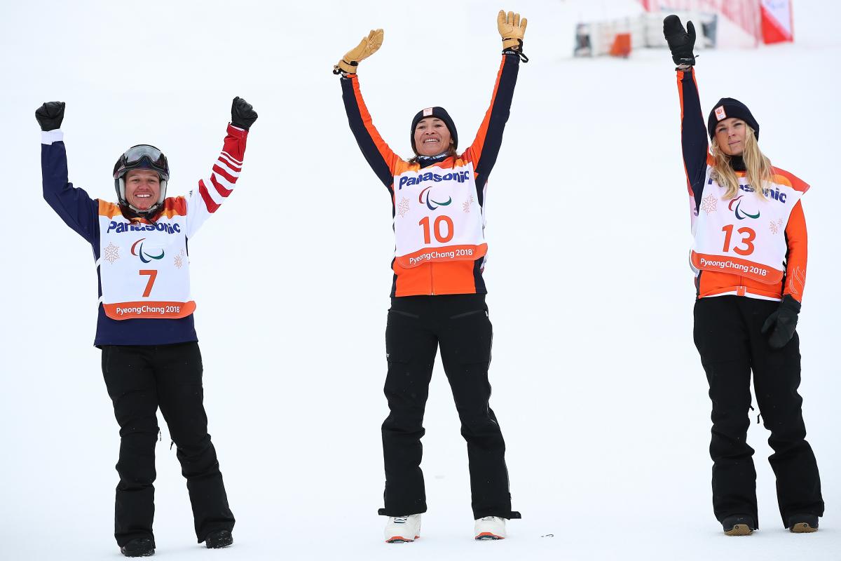 three female snowboarders jump in the air 