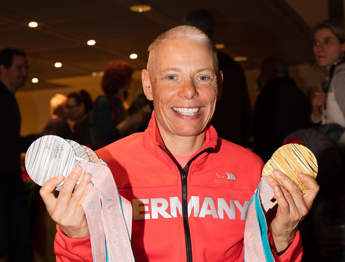 a female athlete holds up her six Paralympic medals