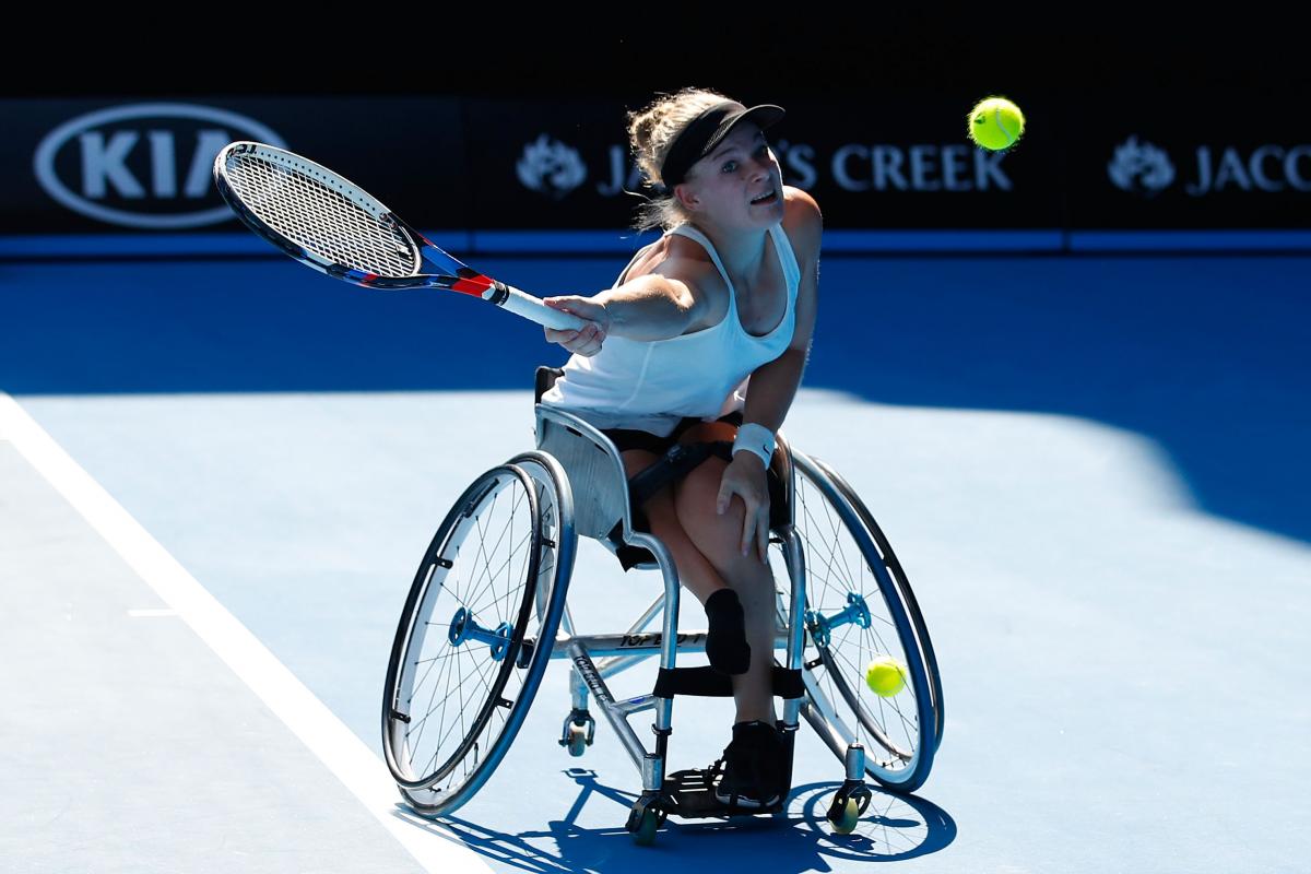 a female wheelchair tennis player makes a shot