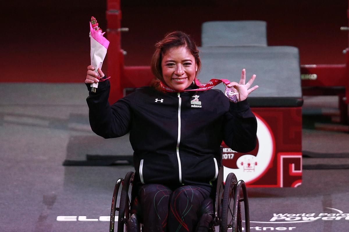 a female powerlifter holds up her gold medal