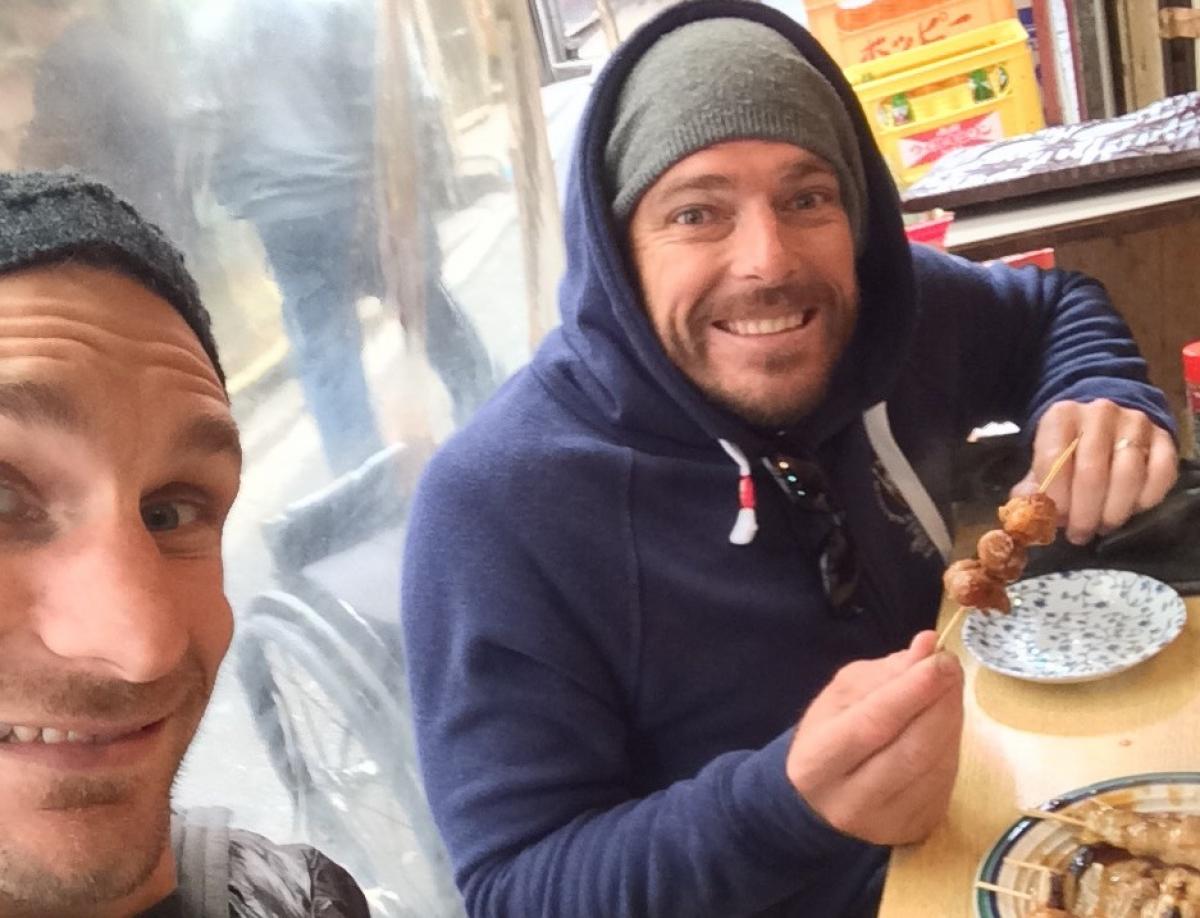 two men take a selfie over food