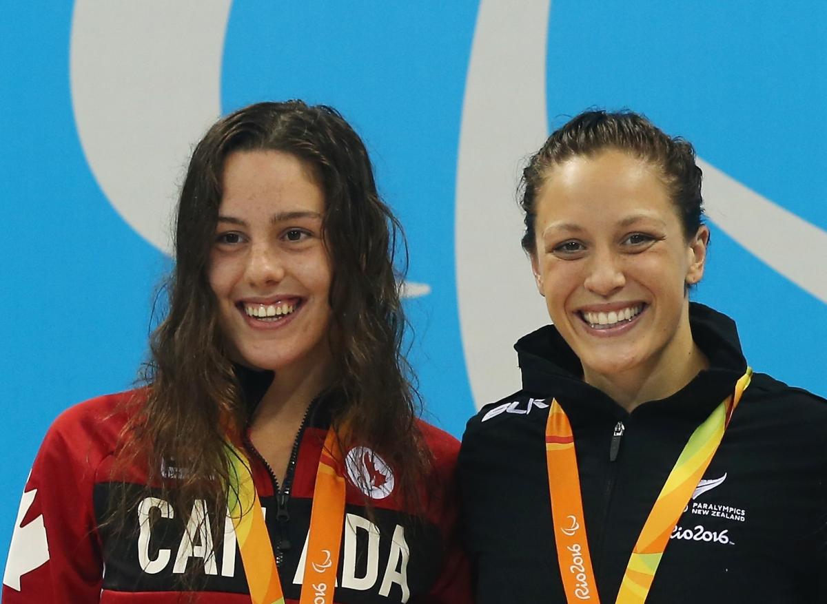 two female Para swimmers smiling on the podium