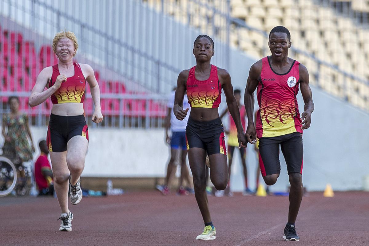 Three athletes running on a track
