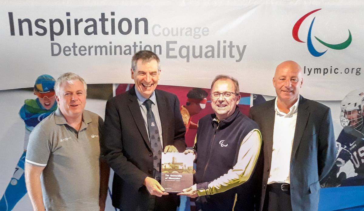 four men holding a plaque