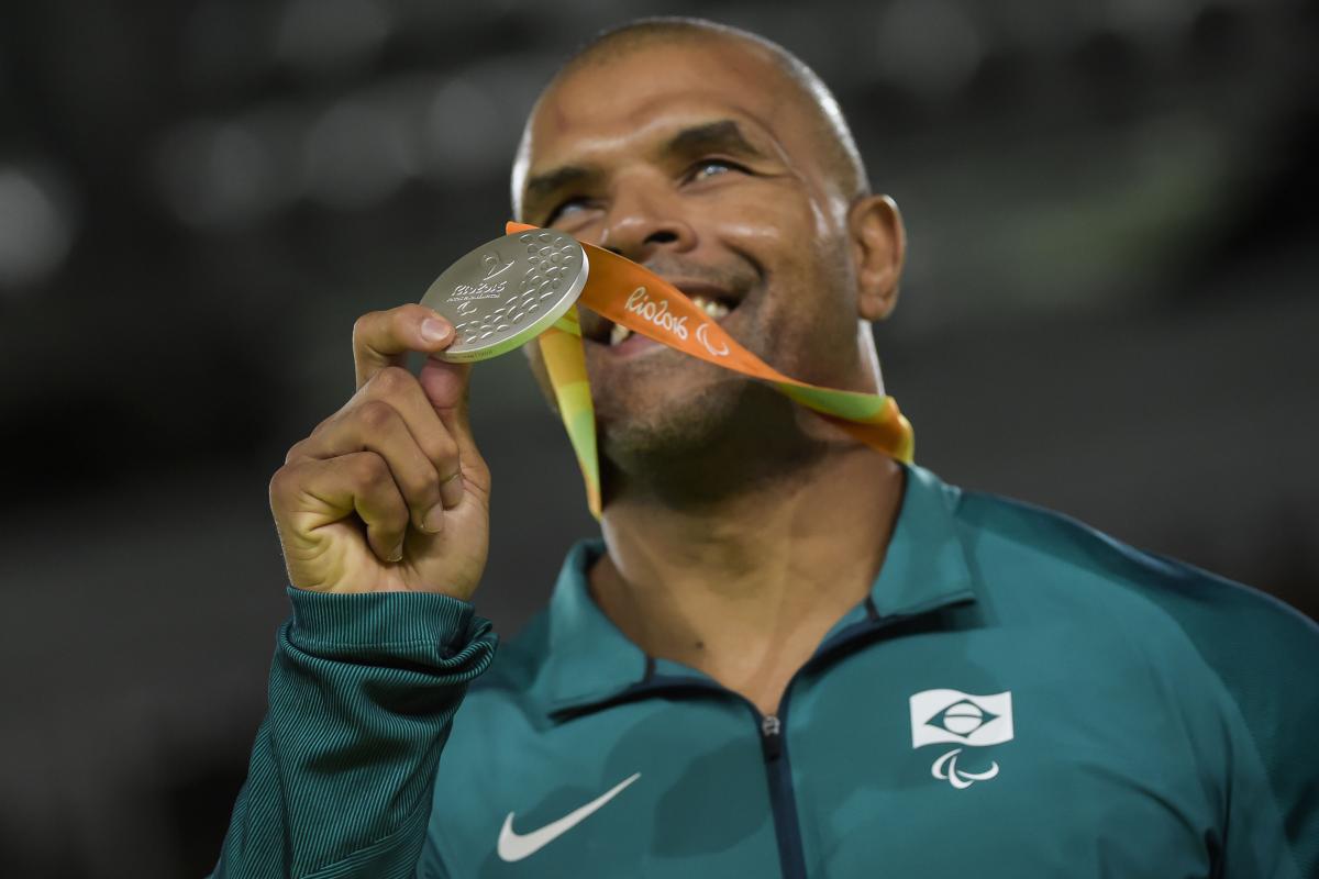 a male judoka holds up a silver medal