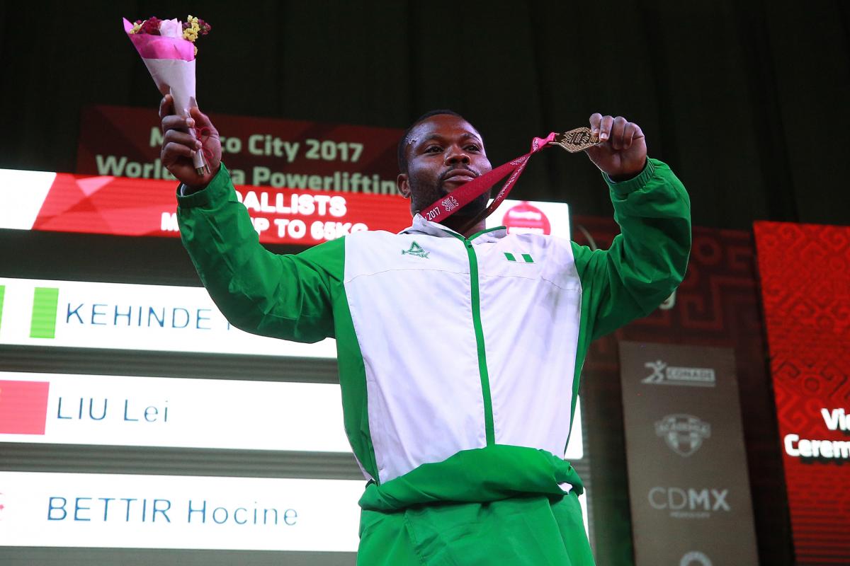 a male powerlifter holds up his gold medal