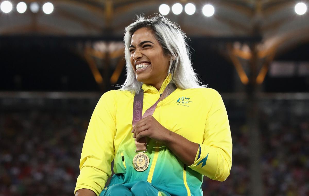 a female wheelchair racer laughs with her gold medal