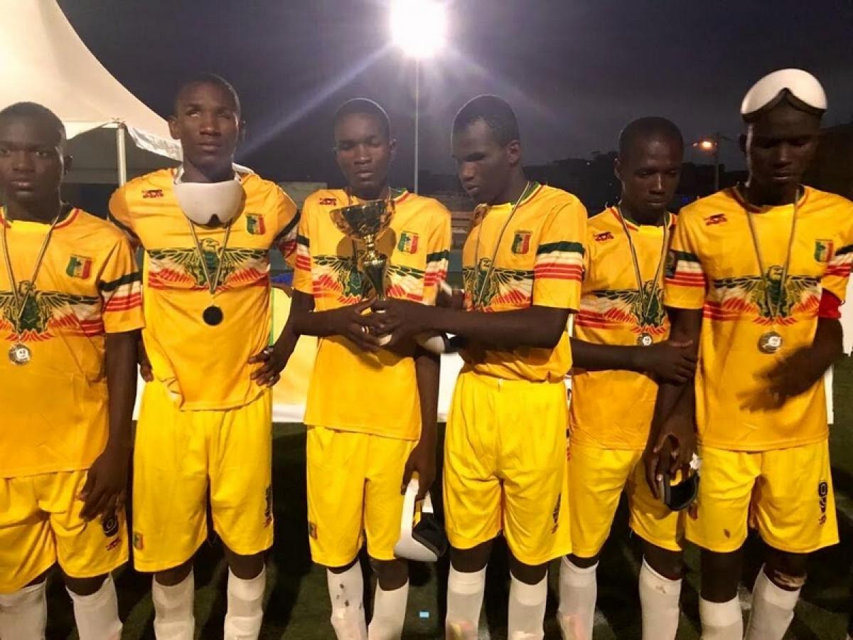 a group of blind footballers hold up a trophy