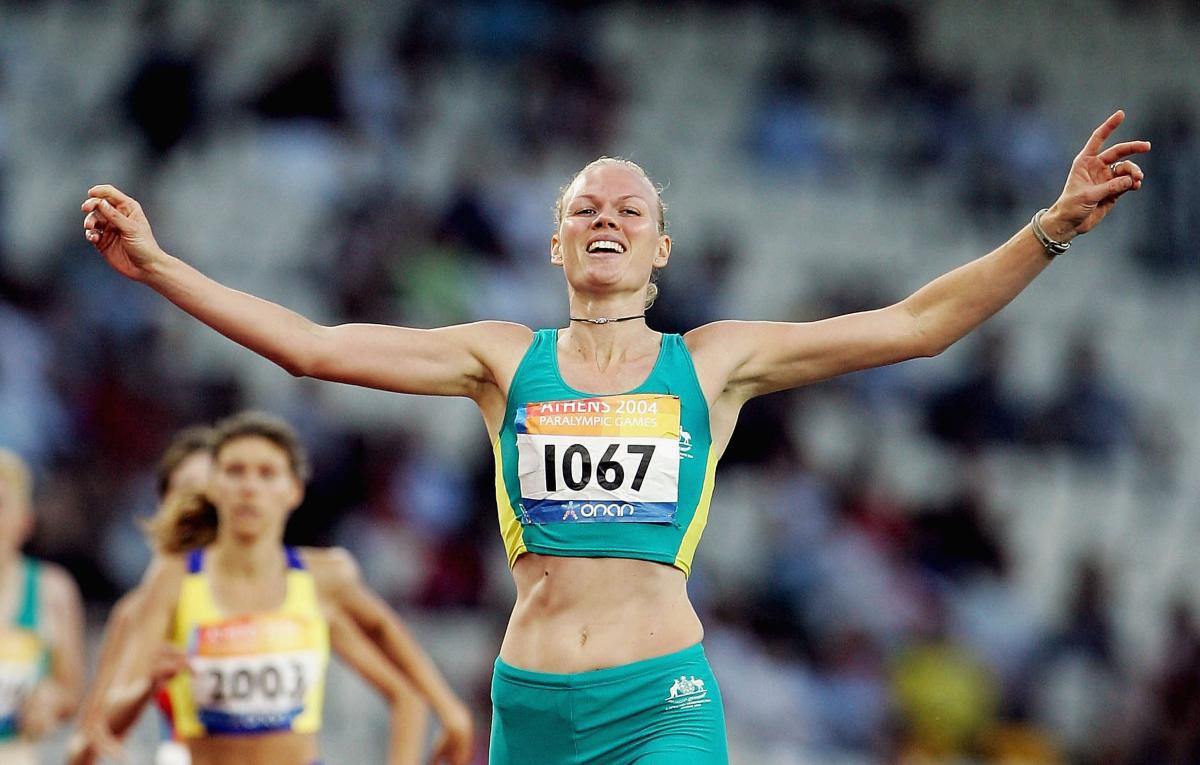a female sprinter crosses the line as winner