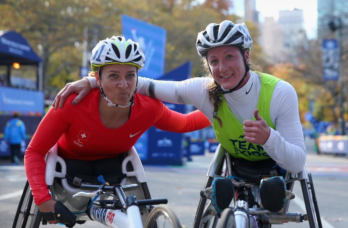 two female wheelchair racers arm in arm at the finish line