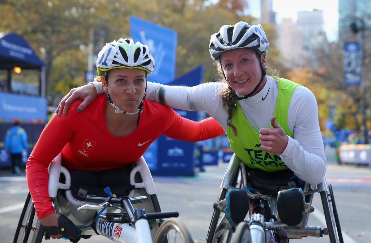 Manuela Schaer and Tatyana McFadden two female wheelchair racers arm in arm at the finish line