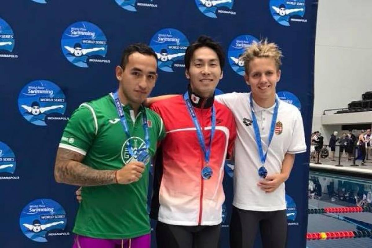 Three swimmers posing in front of a banner