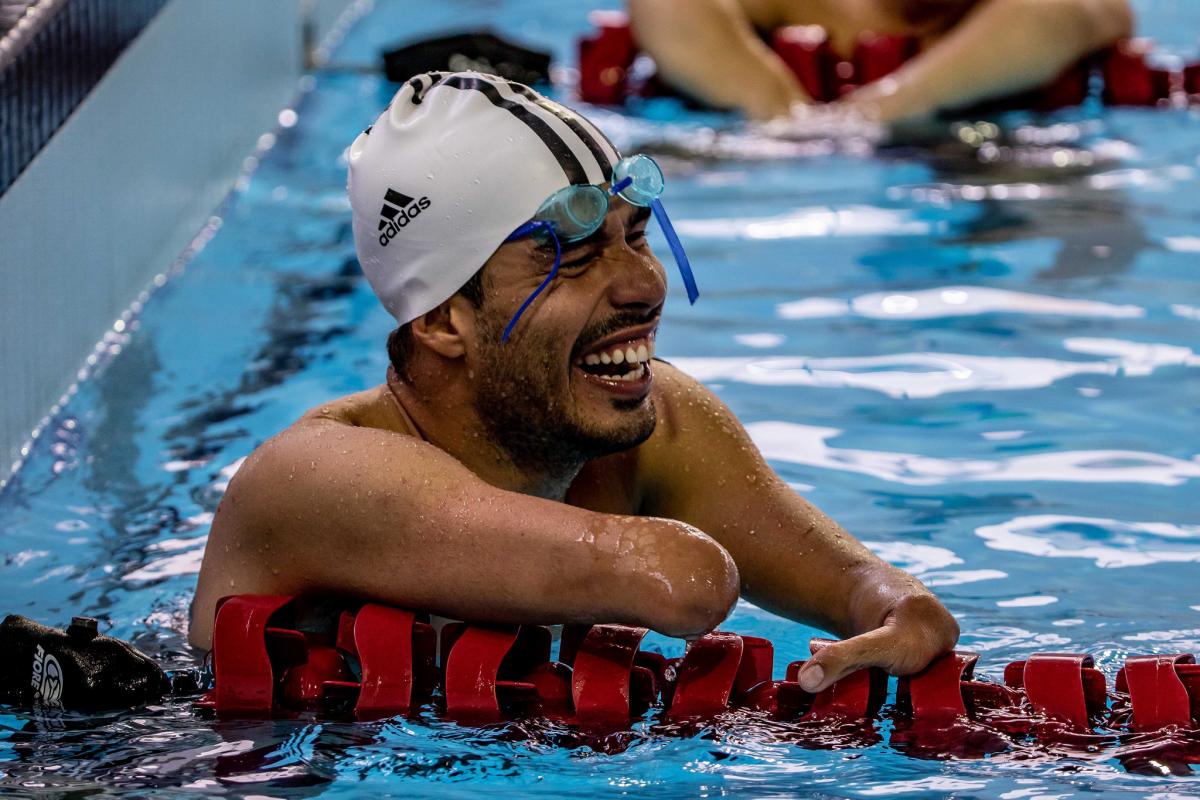 a male Para swimmer laughs in the pool