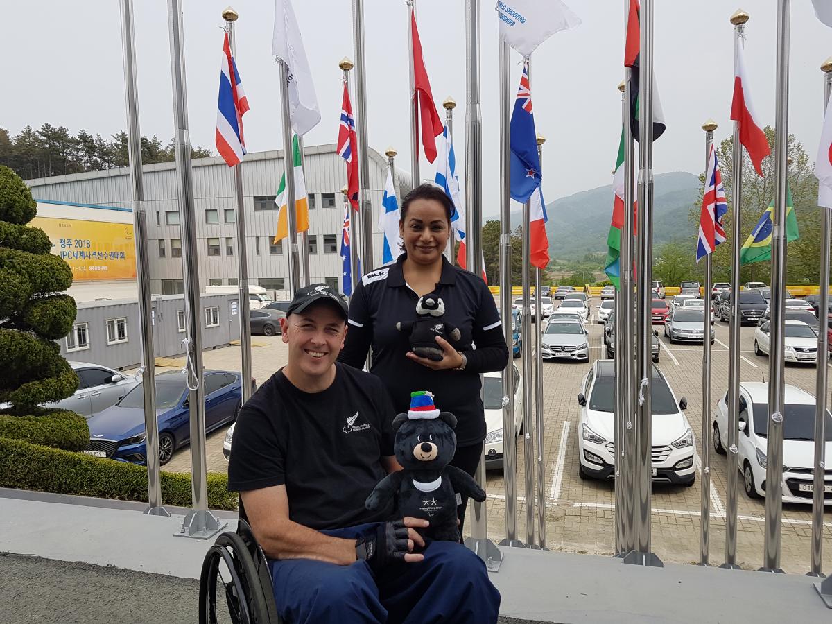 Michael Johnson a male Para athlete and a woman standing both holding mascots