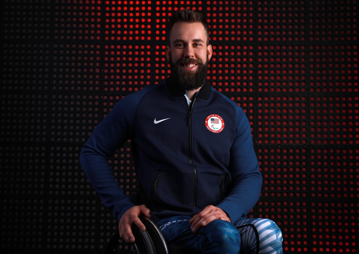 a male wheelchair athlete smiles at the camera