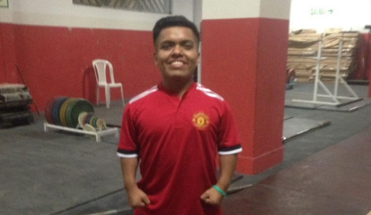 a male powerlifter standing in a Manchester United shirt