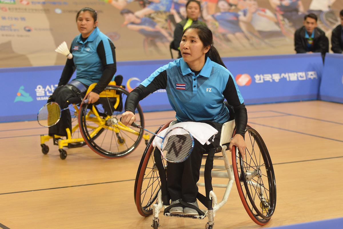 Woman badminton player in wheelchair hits a birdie