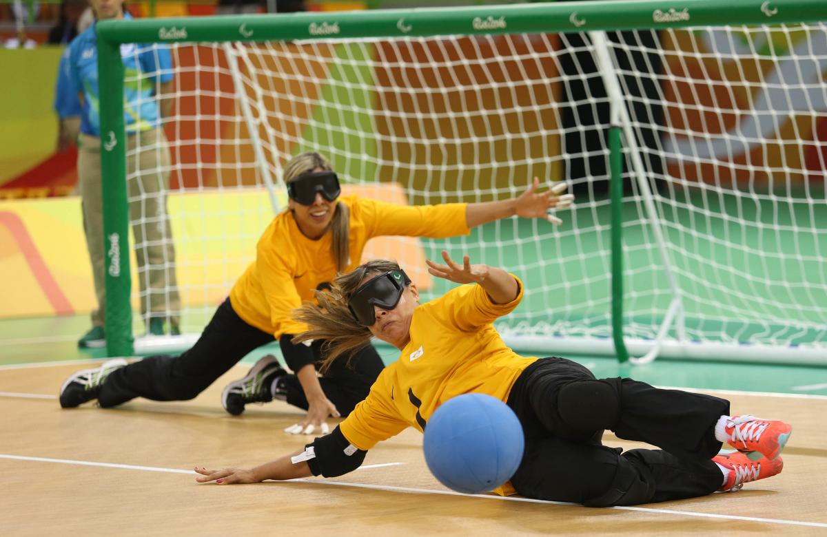 two female goalball players trying to stop a shot