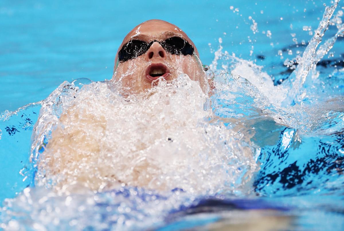 a male Para swimmer mid-backstroke