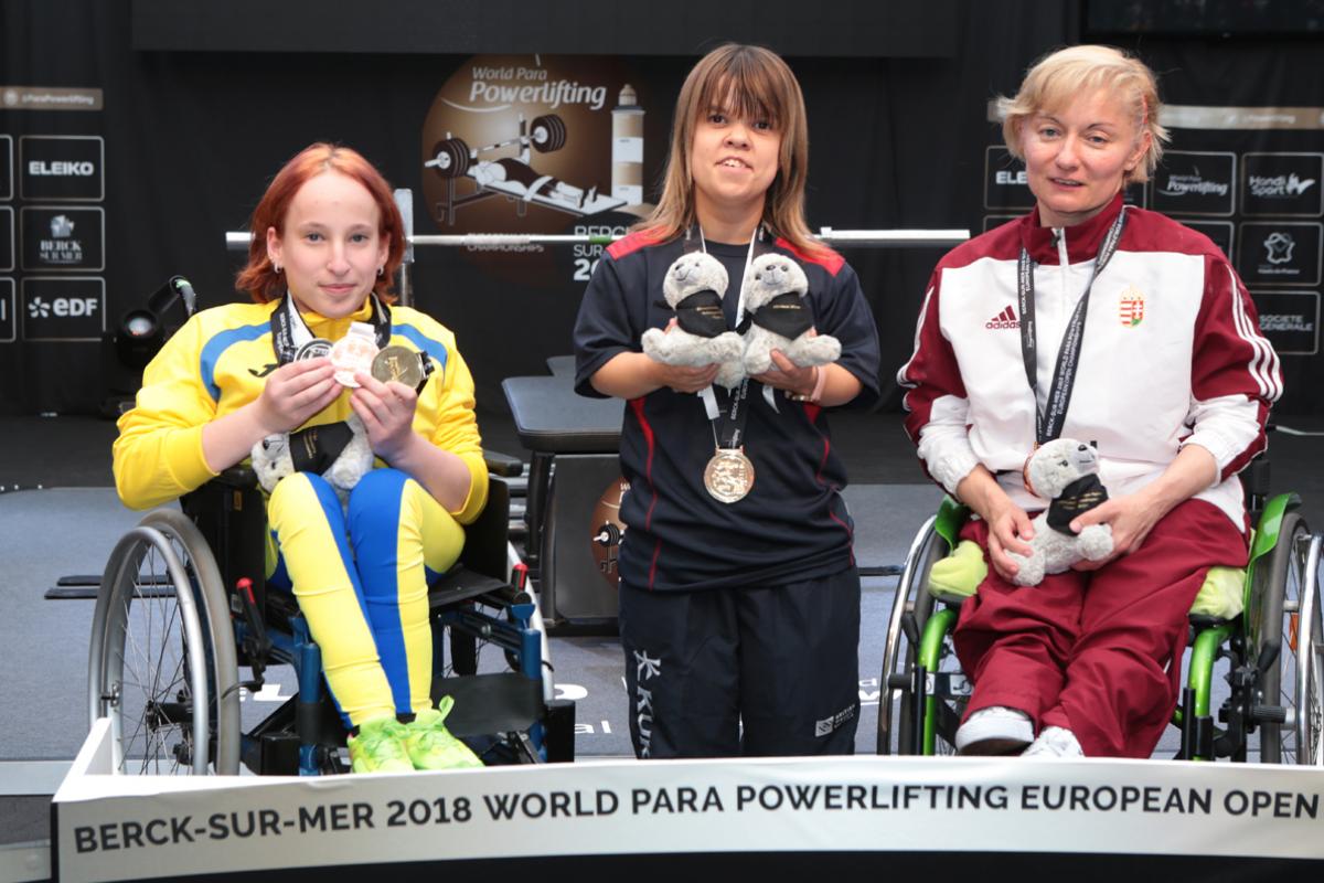 three female powerlifters on the podium