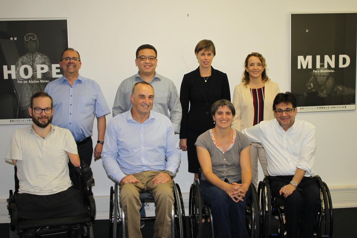 A group of eight people both standing and sitting smile for the camera