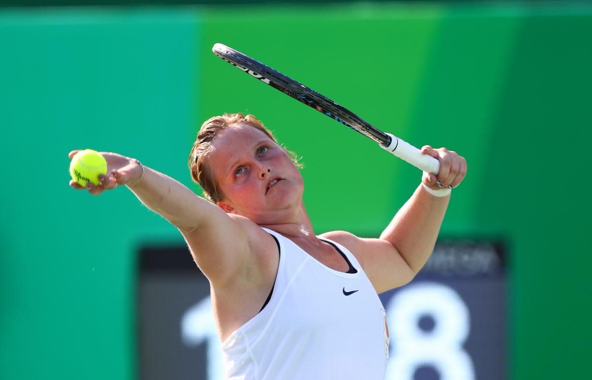 a female wheelchair tennis player prepares to serve