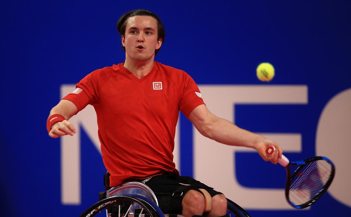 a male wheelchair tennis player takes a shot