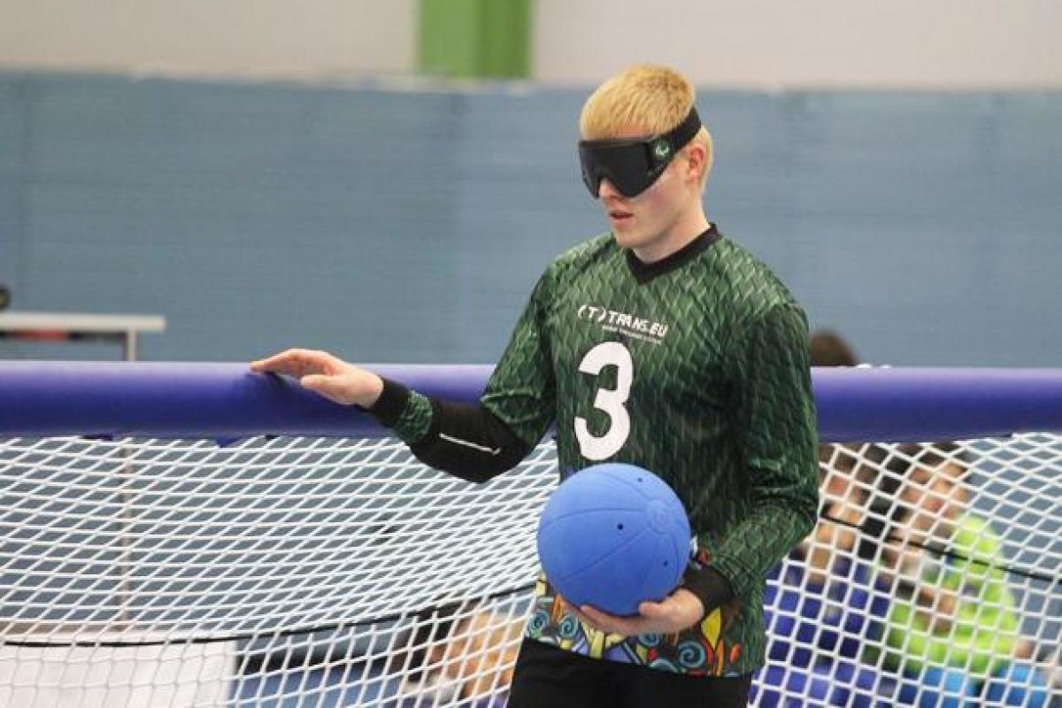 a male goalball player stands at the net