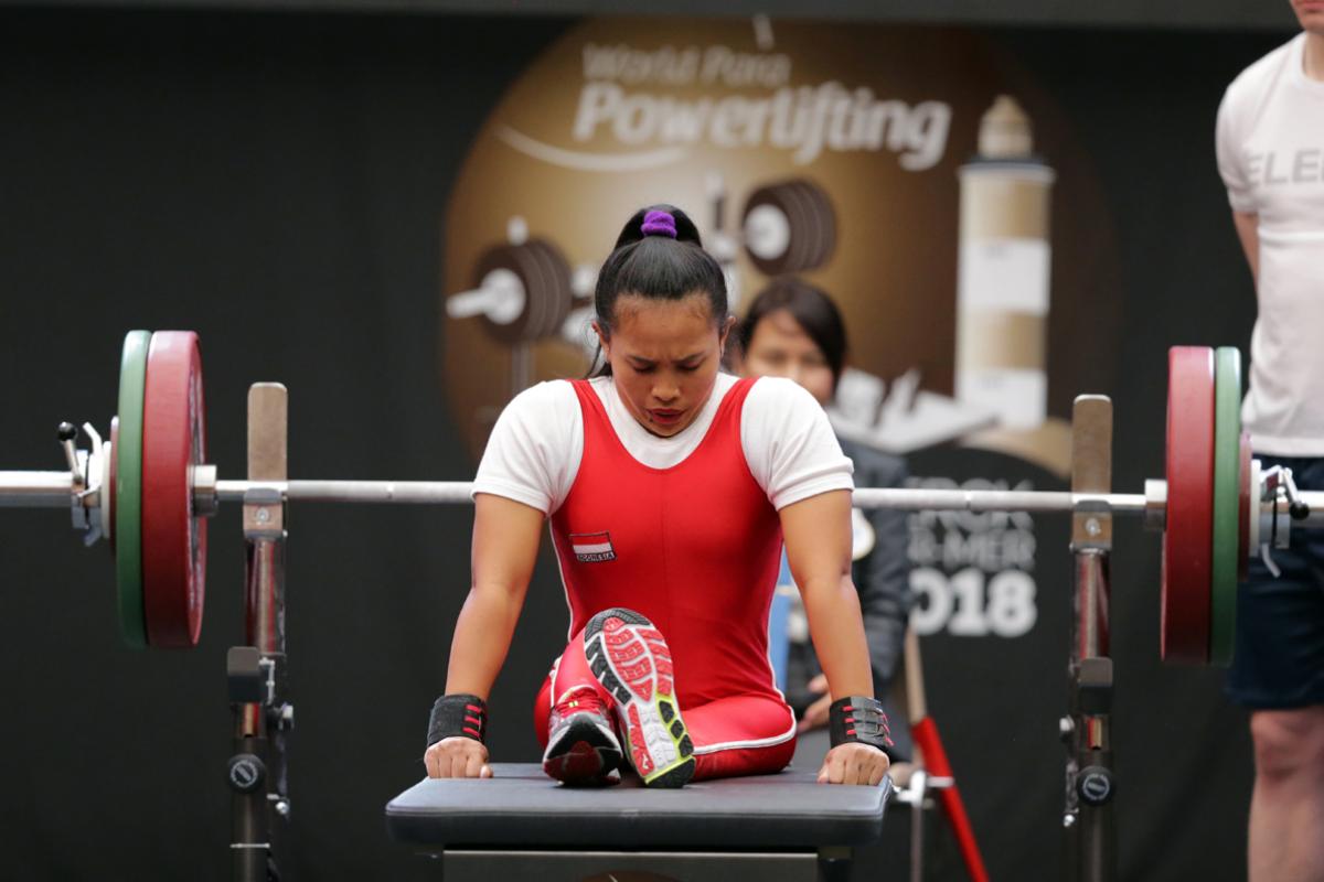 a female powerlifter prepares to lift by sitting on the bench