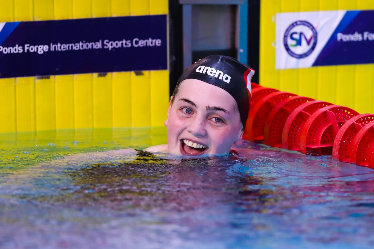 a female swimmer smiles in the pool after winning her race