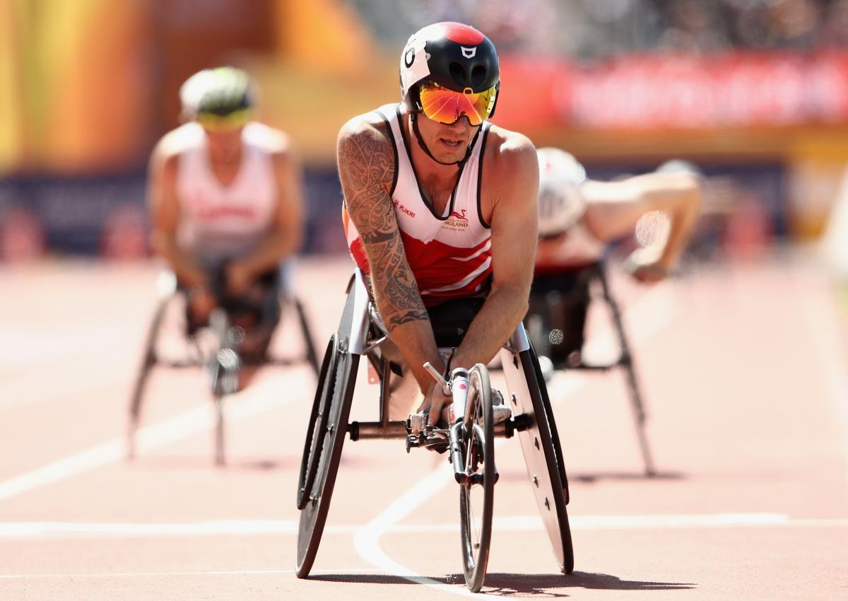 a male wheelchair racer crosses the finish line