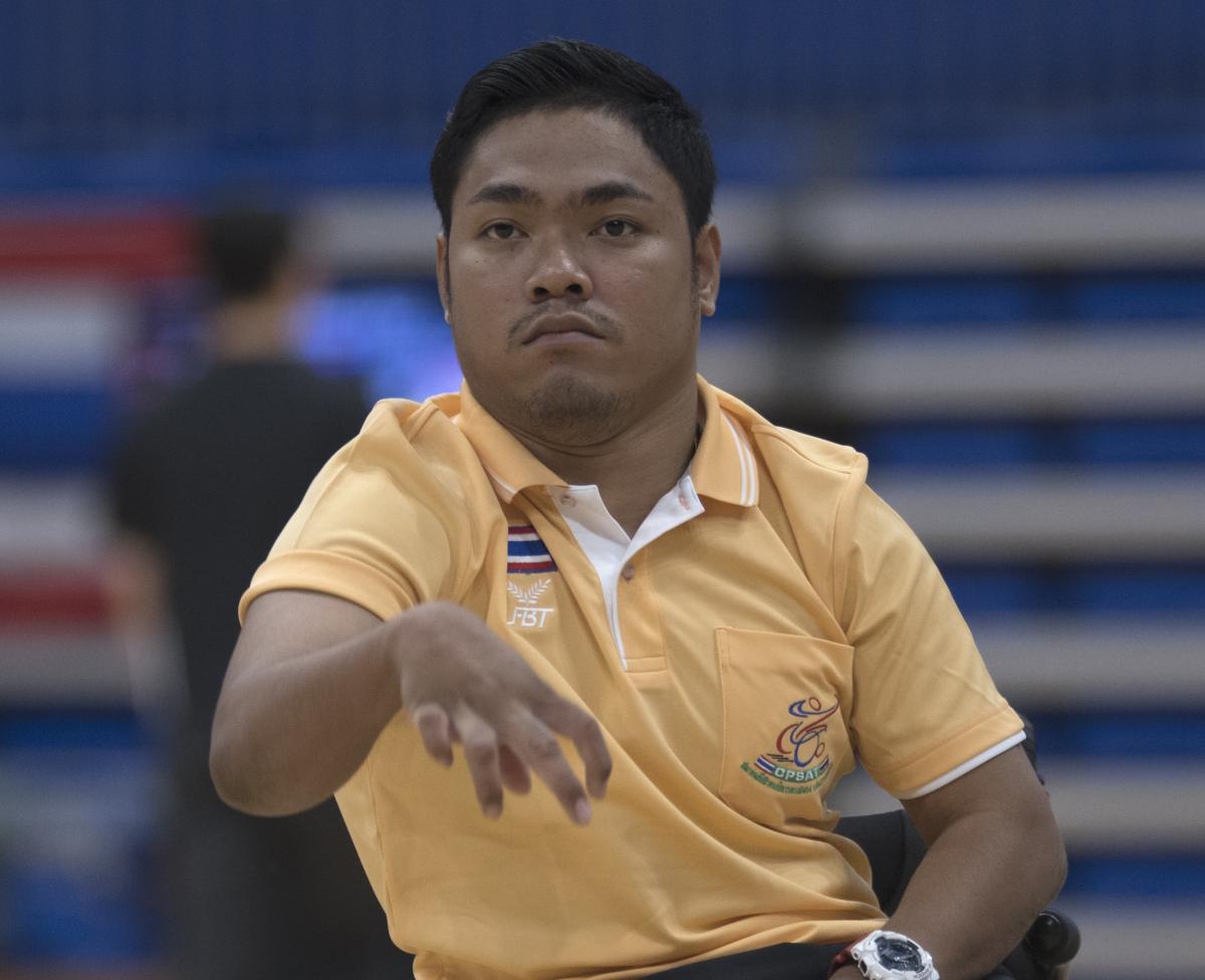 a male boccia player throws a ball