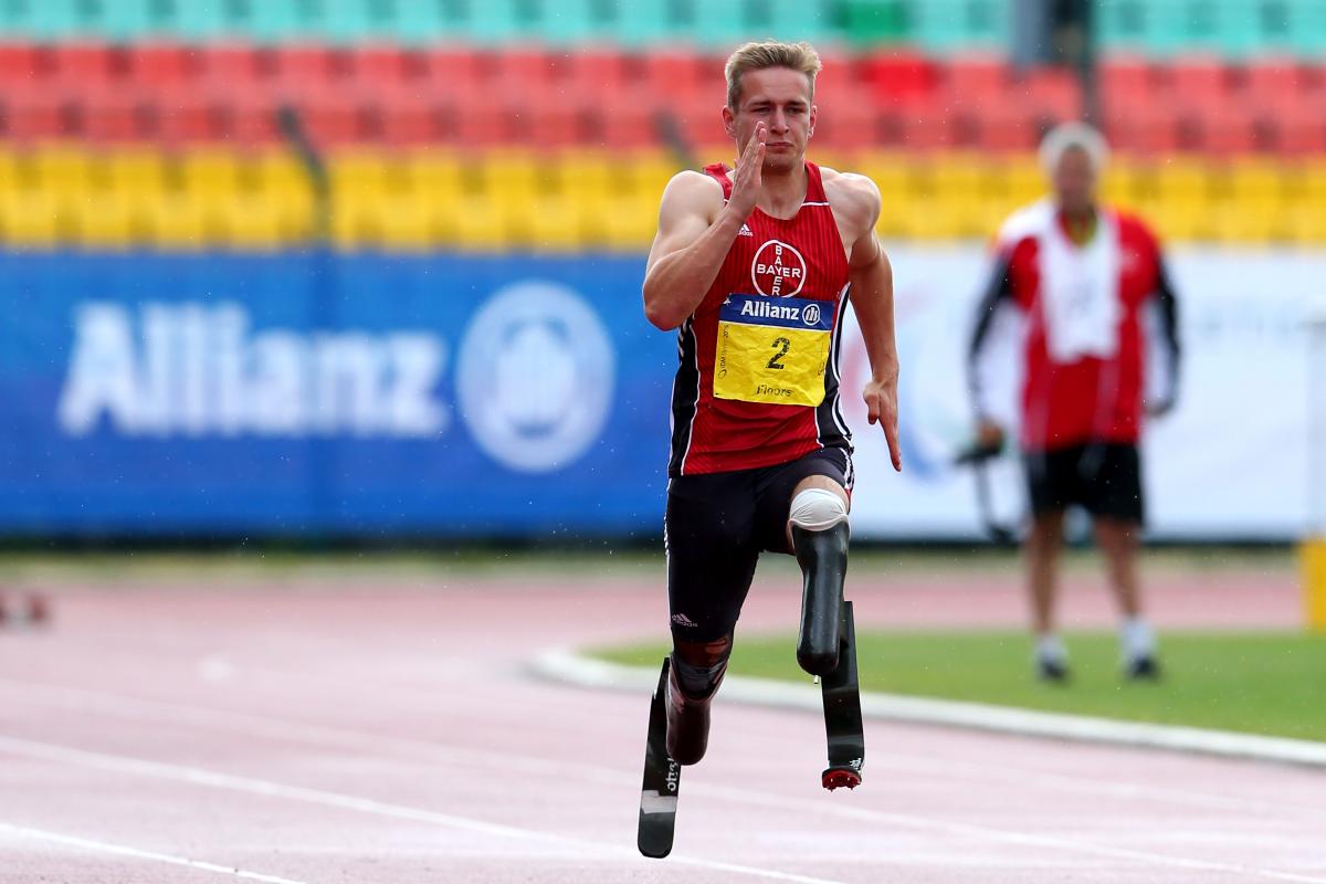 a male double amputee sprinter runs towards the finish line