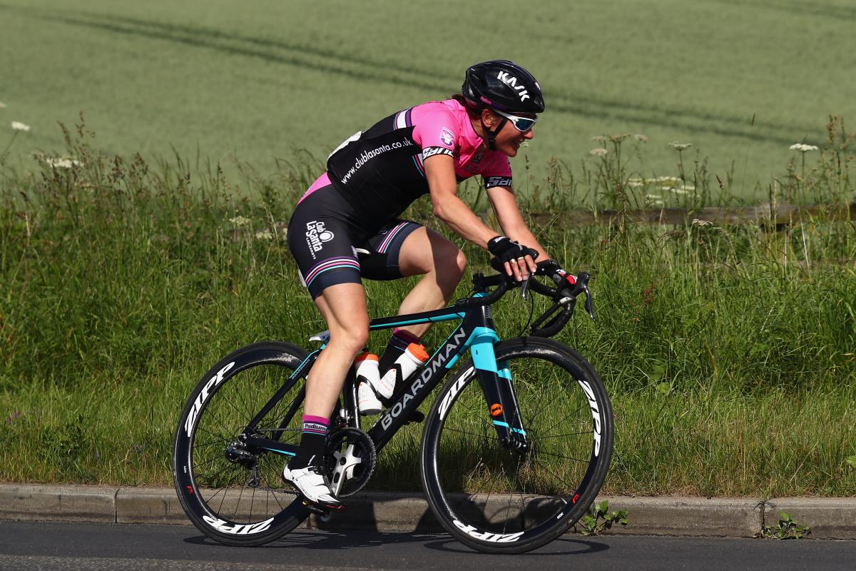 a female Para cyclist rides down a road