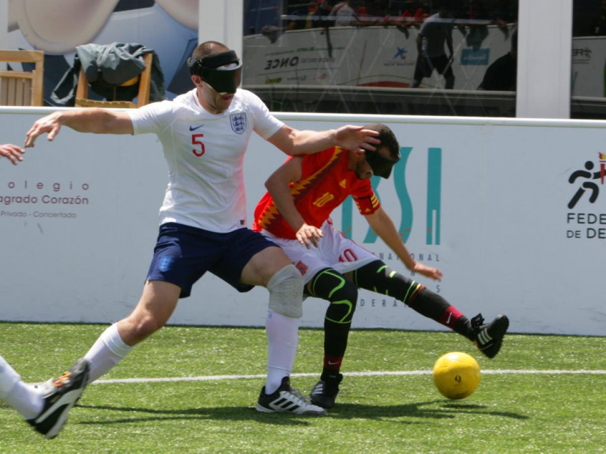 two male blind footballers battling for the ball 