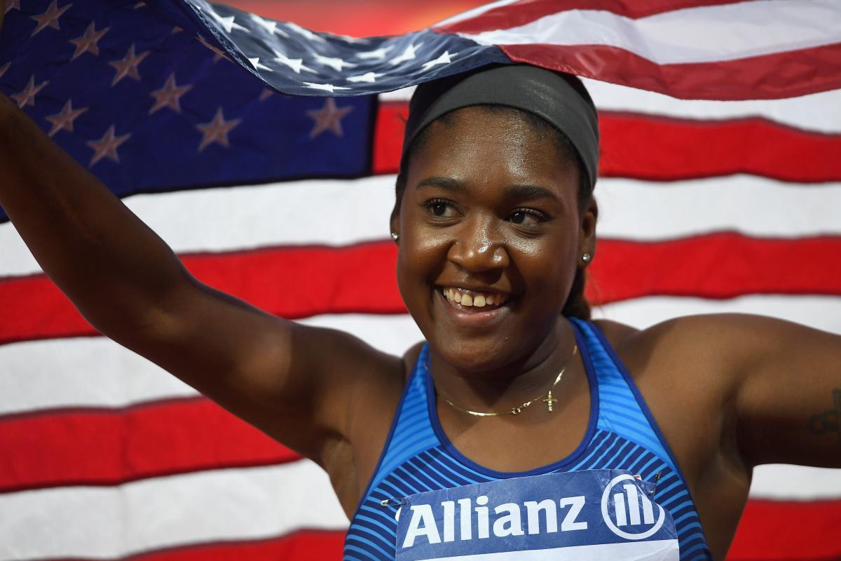 Deja Young a female Para athlete smiling and holding an American flag