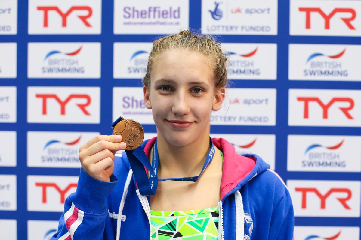 Louise Fiddes - 2018 Sheffield World Series a female Para swimmer holds up a medal and smiles