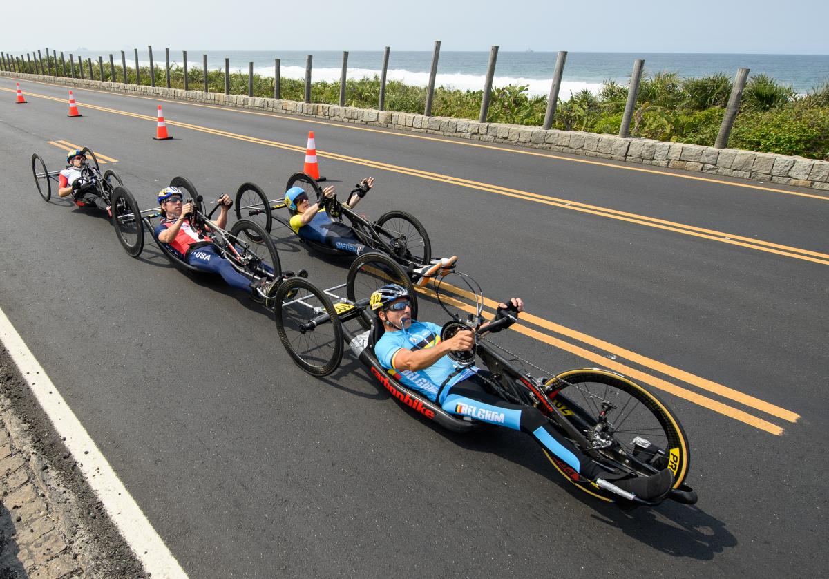 a group of male Para cyclists race along the road