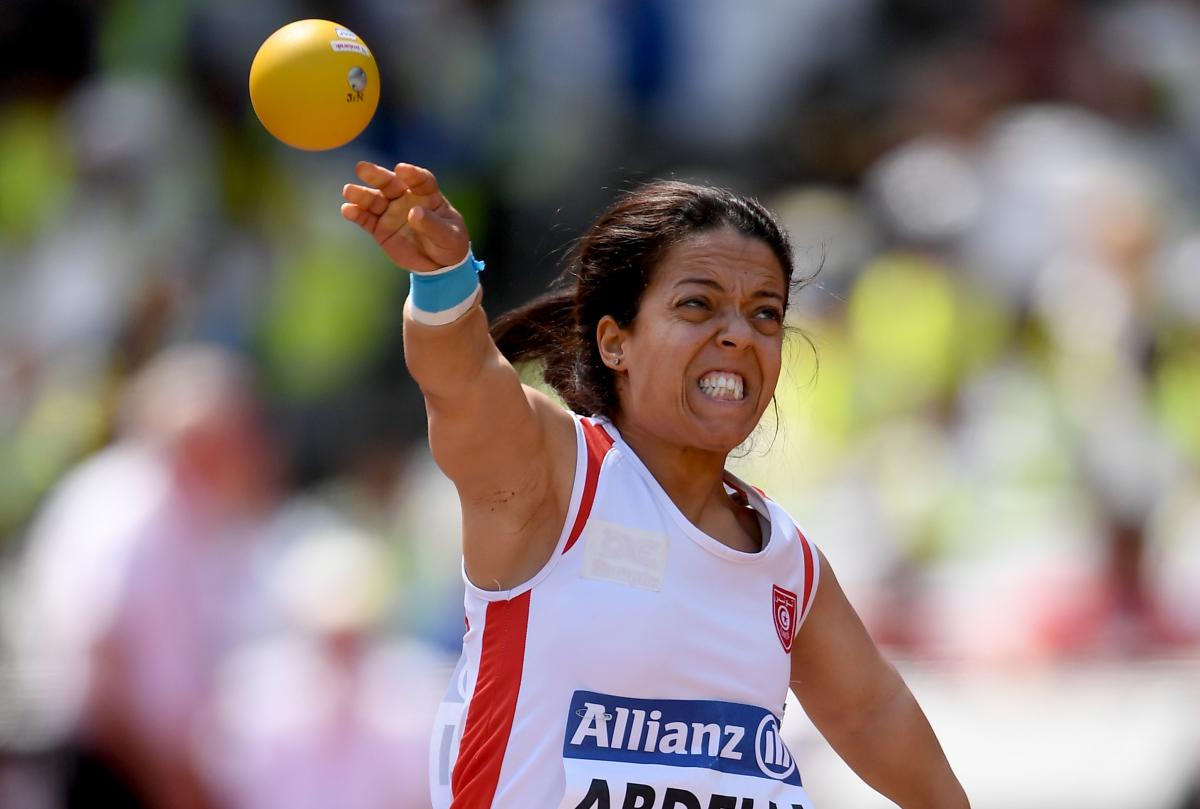 a female Para athlete of short stature throws a shot put