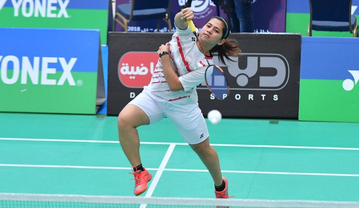 Female badminton player jumps to hit a birdie