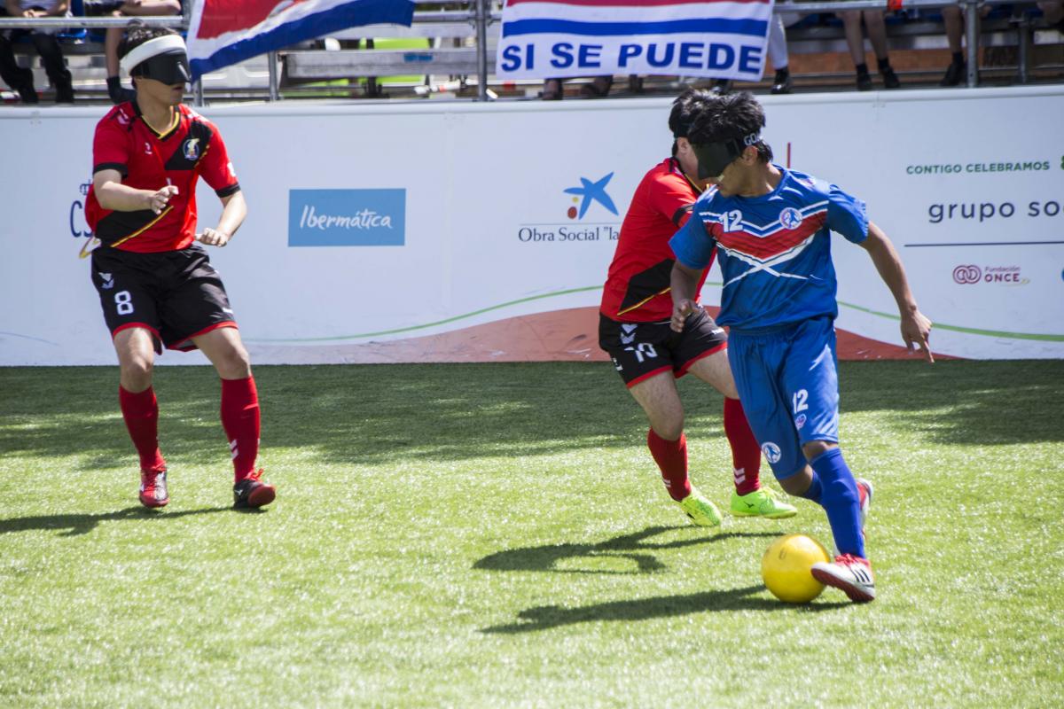 a male blind footballer runs with the ball