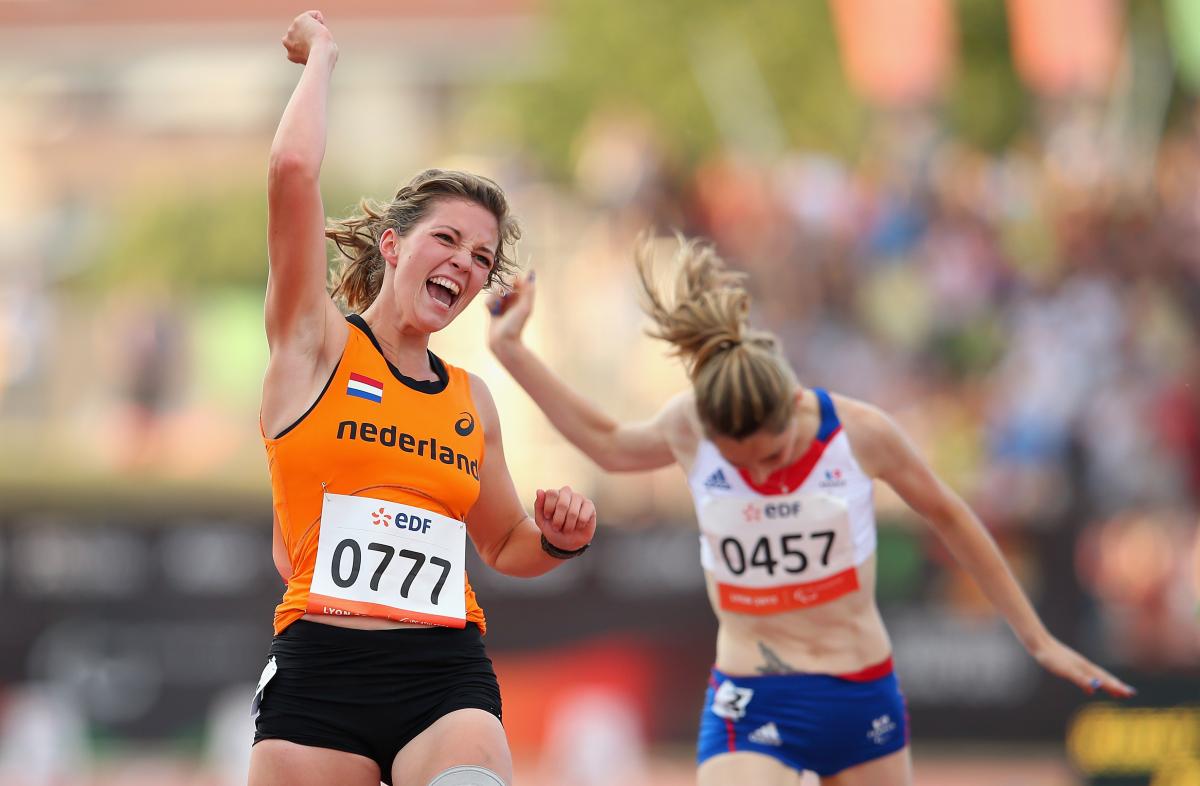 a female amputee sprinter punches the air as she crosses the finish line
