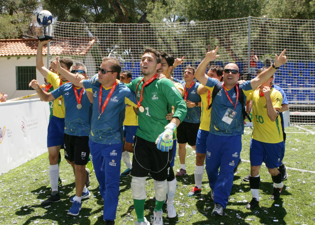 a group of male blind footballers celebrating on the football pitch
