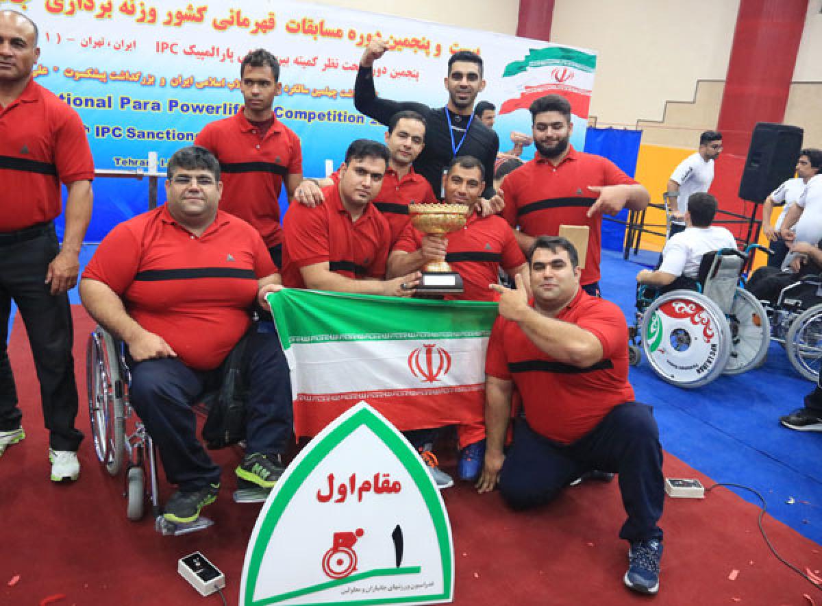 Iran national powerlifting competition a group of male powerlifters holding an Iran flag and a trophy