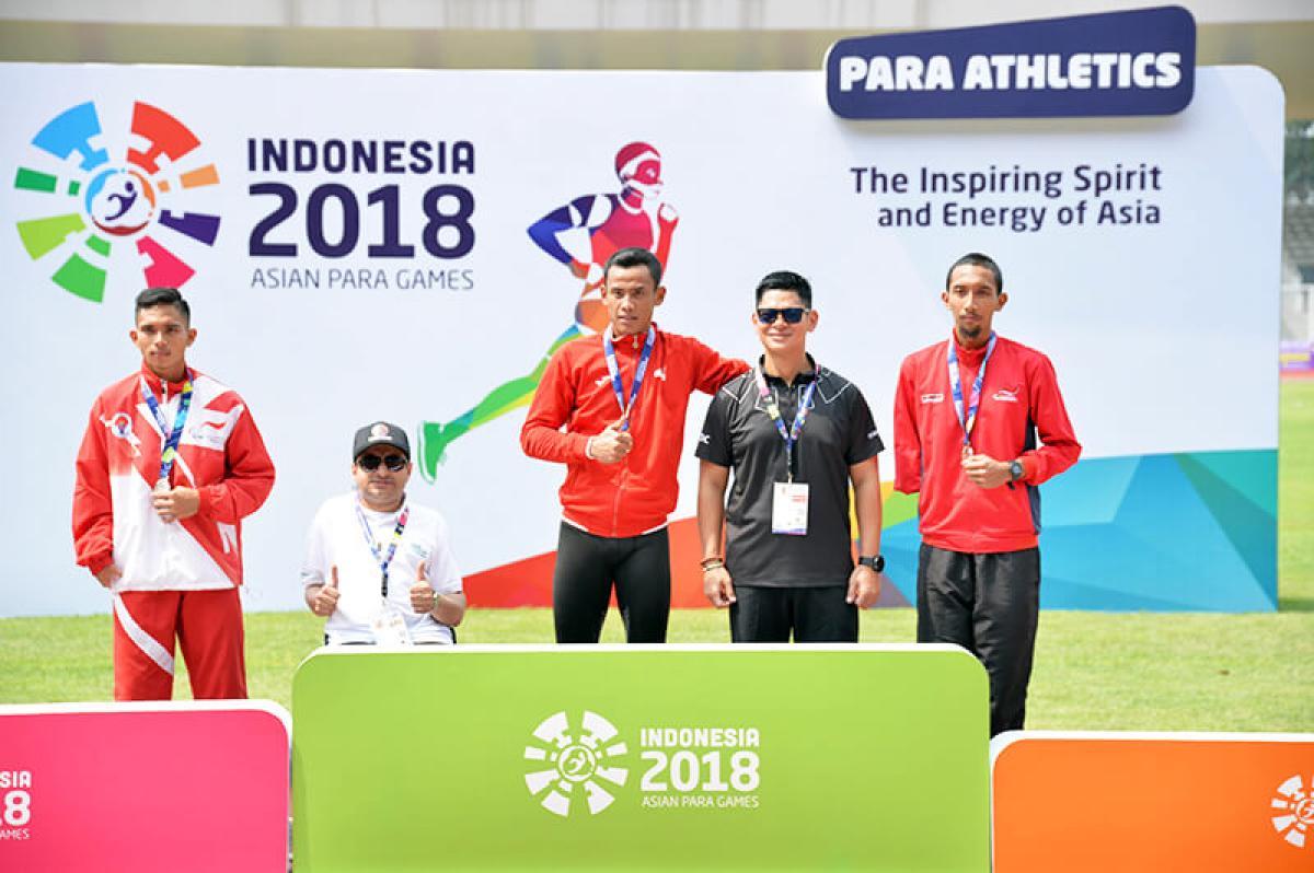 Athletes and their guides pose on the podium