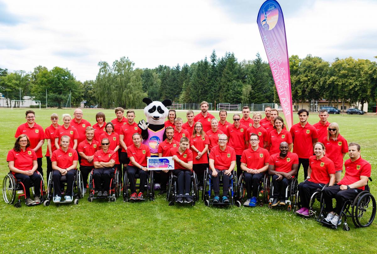 Group athletes standing and in wheelchairs meet Max the Para panda mascot